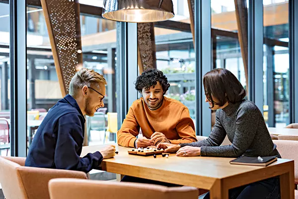 Kolme henkilöä pelaa lautapeliä