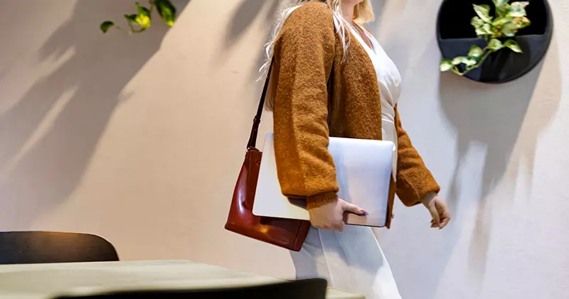 A woman walks with a laptop in her hand