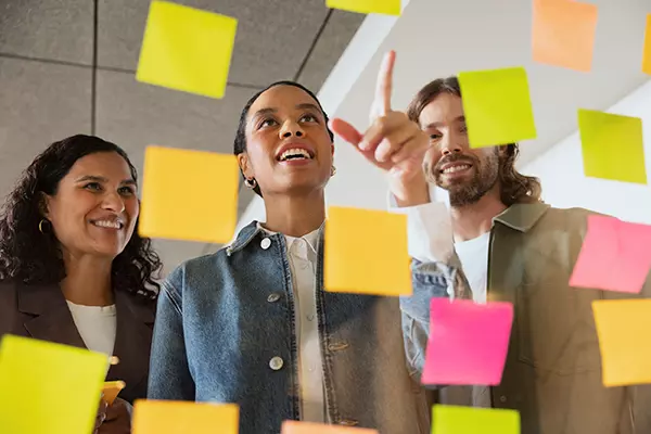 Three people are looking at post-it notes