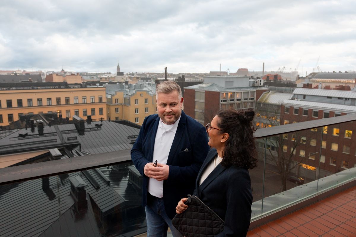 Kaksi henkilöä korkean talon terassilla Helsingin kattojen yllä